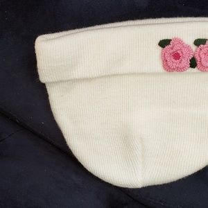 White knit hat trimmed with 2 pink flowers